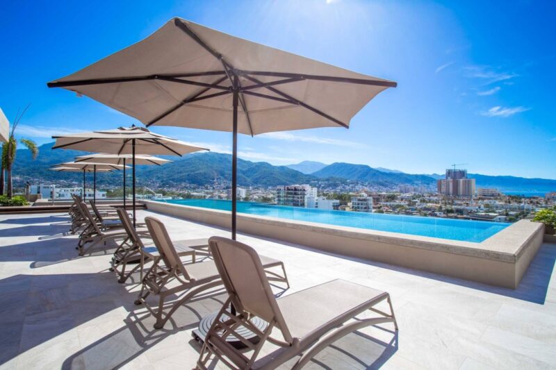 The Roma Encore rooftop infinity pool and loungers, with the mountains beyond